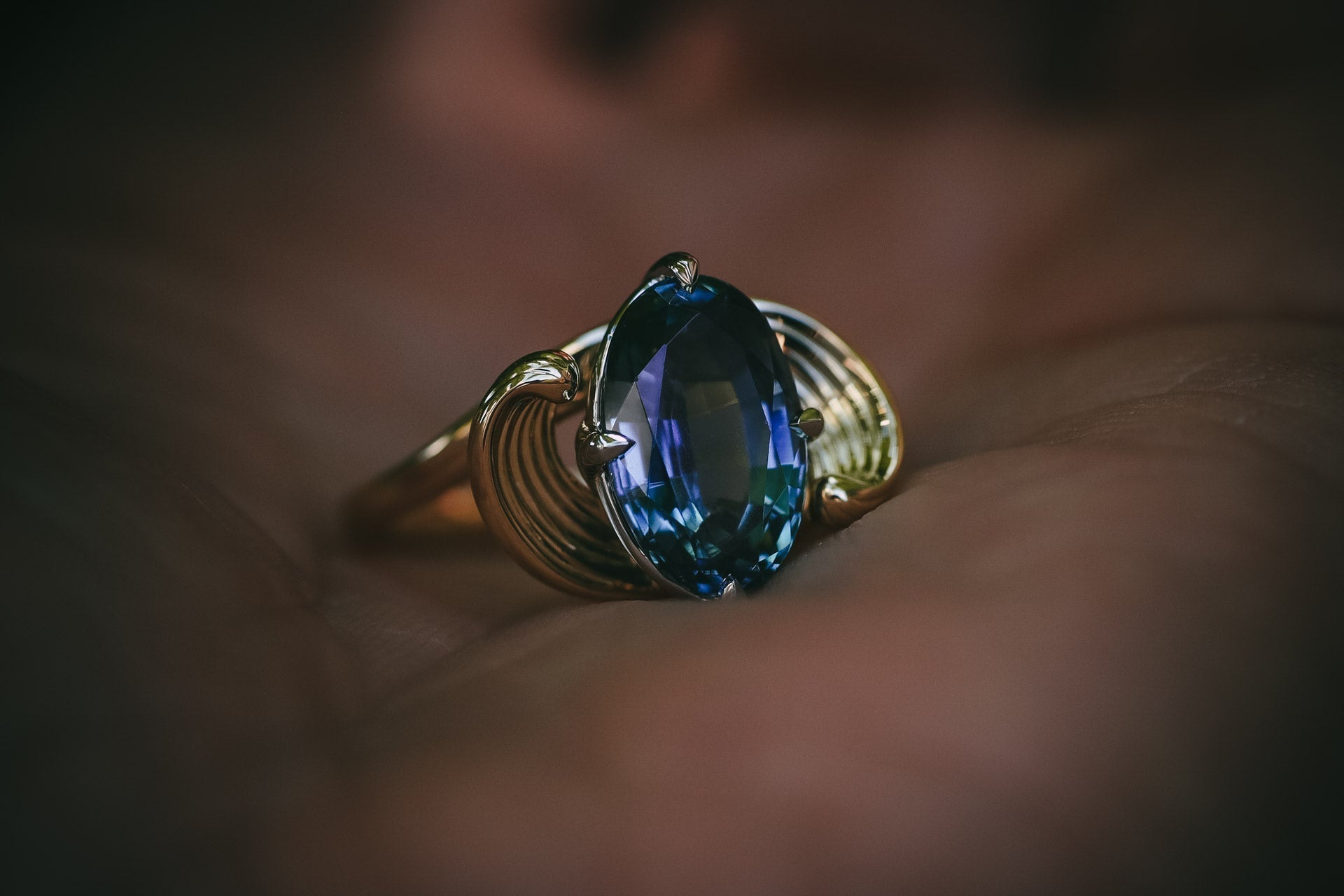Moira Patience teal sapphire carved flowing engagement ring in hand