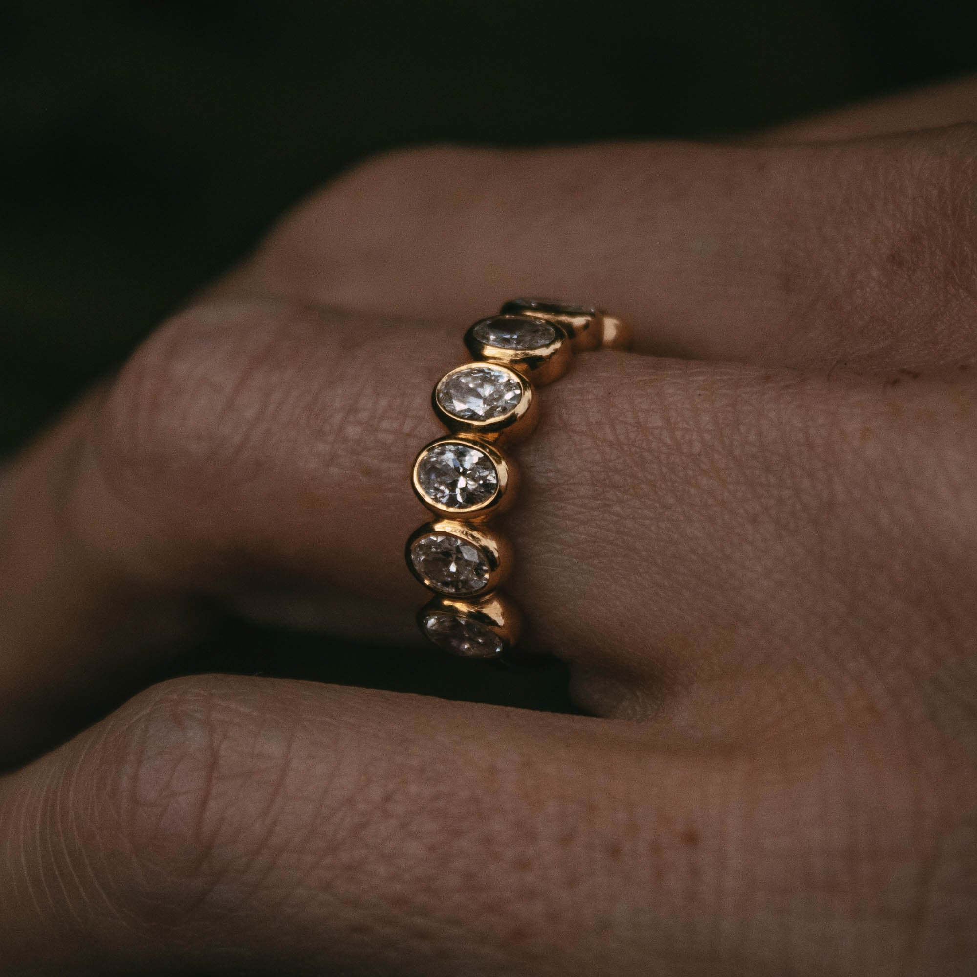 Jura seven oval diamond half-eternity ring in 18ct yellow gold, close-up worn on the finger