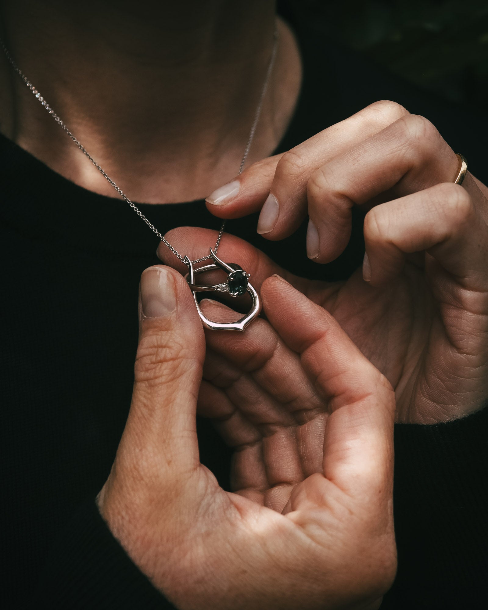 Ring Keeper pendant and chain in 18ct white gold, shown while a ring is threaded through the pendant