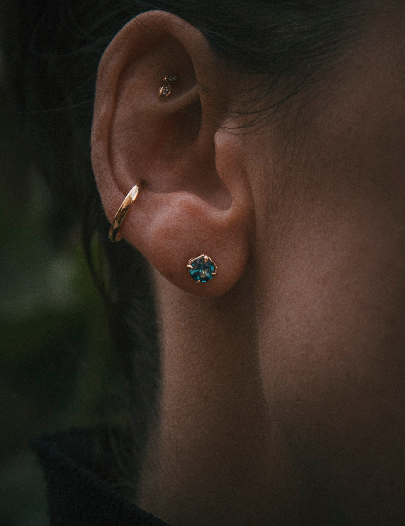 Petal round teal sapphire stud earrings in 18ct yellow gold, worn at the ear from behind