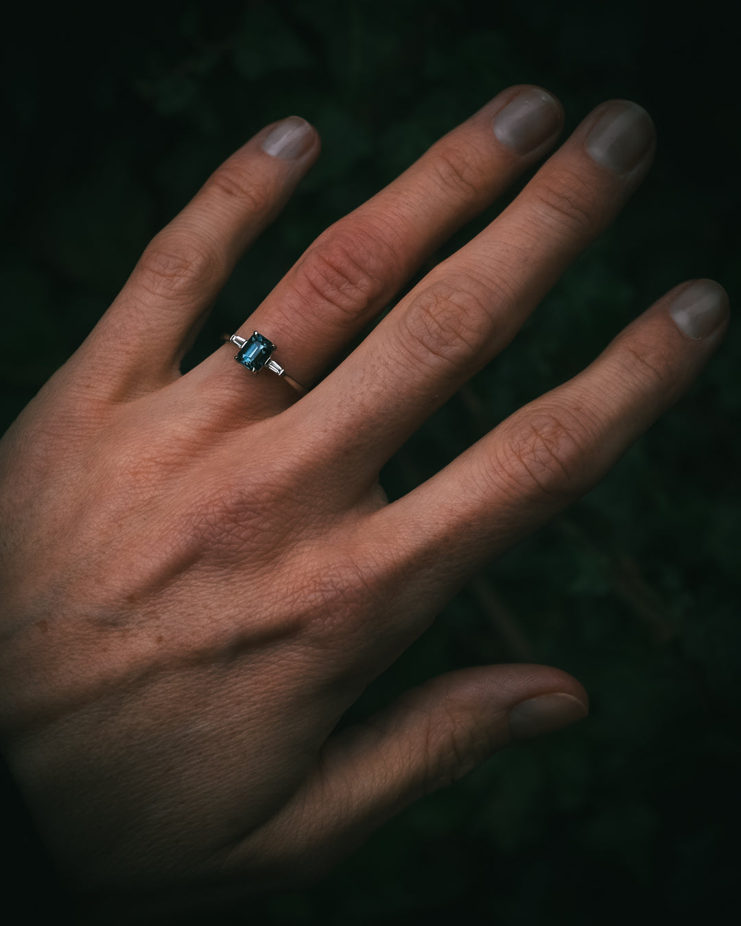 Sròn octagon step-cut teal sapphire ring in platinum with tapered baguette diamonds on hand