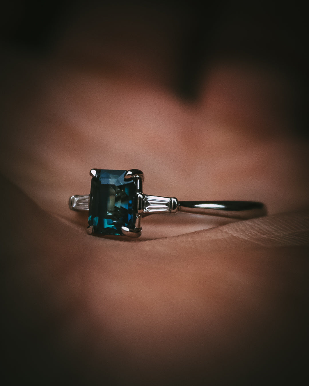 Sròn teal sapphire three-stone ring; platinum Arc setting side profile in hand