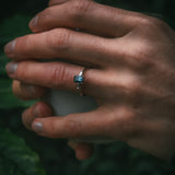 Sròn octagon step-cut teal sapphire ring holding cup