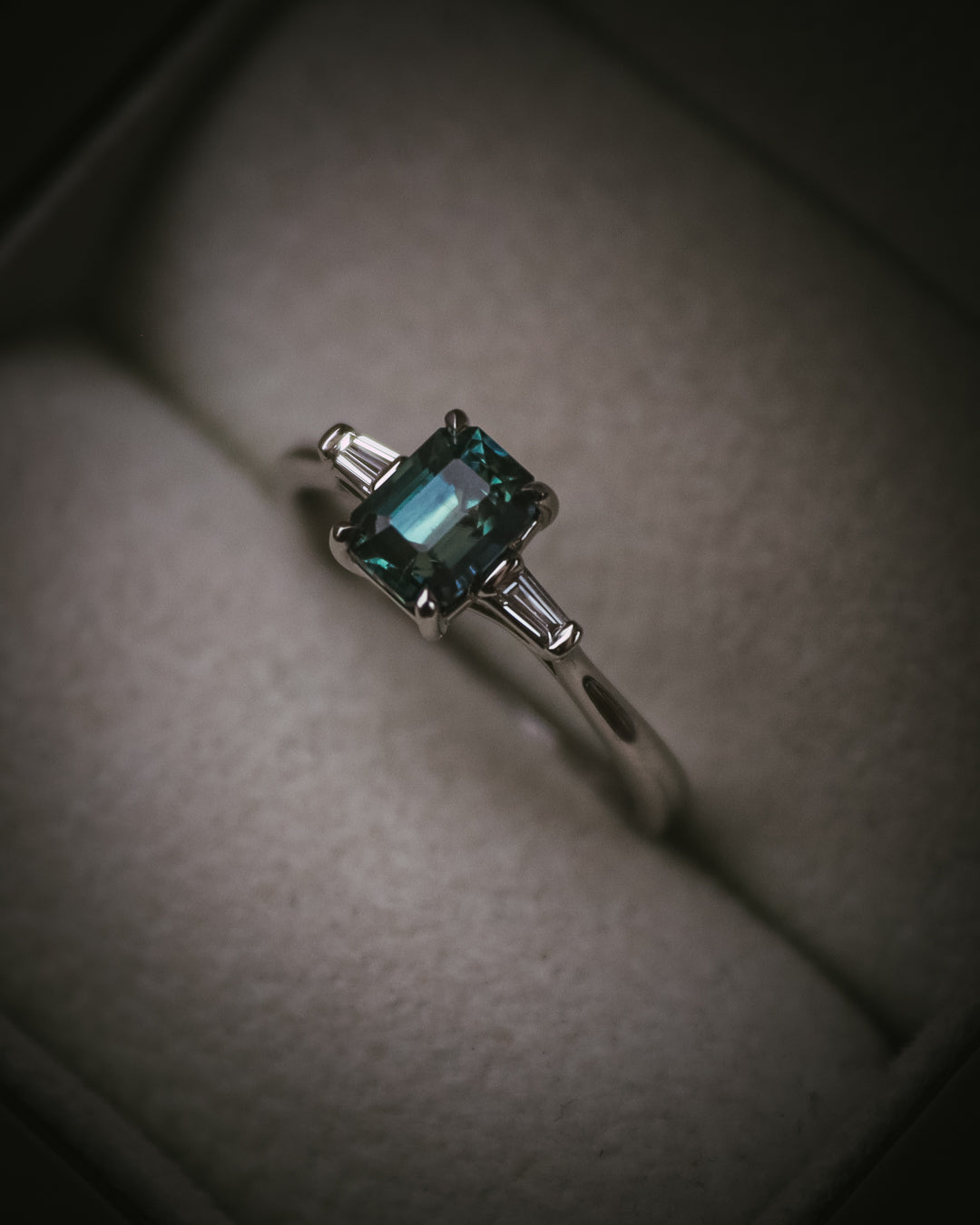 Sròn teal sapphire three-stone ring; platinum Arc setting side profile in box