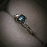 Sròn teal sapphire three-stone ring; platinum Arc setting side profile in box