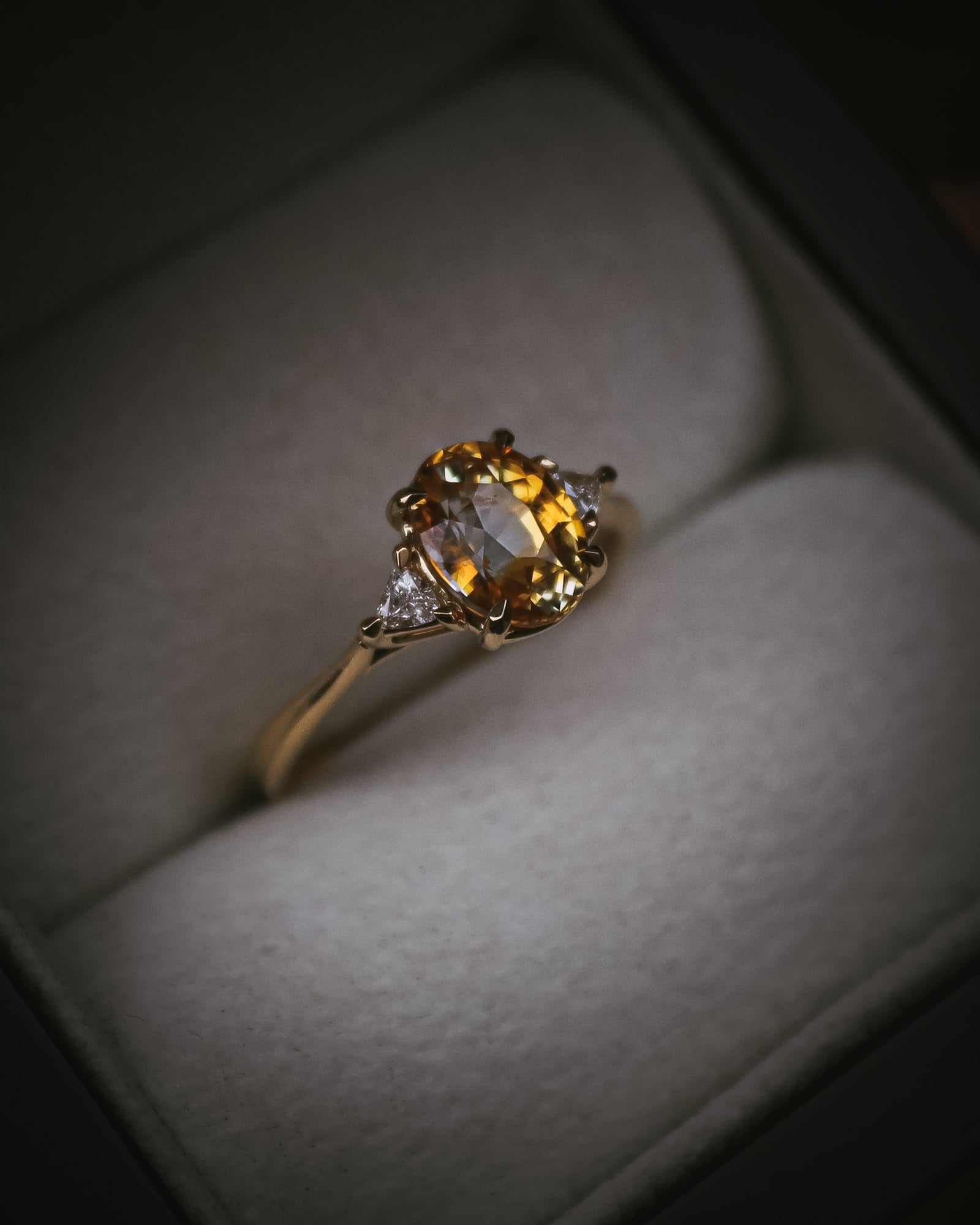 Fidra 2.04ct oval mixed-cut yellow and orange sapphire with trillion-cut diamond side stones