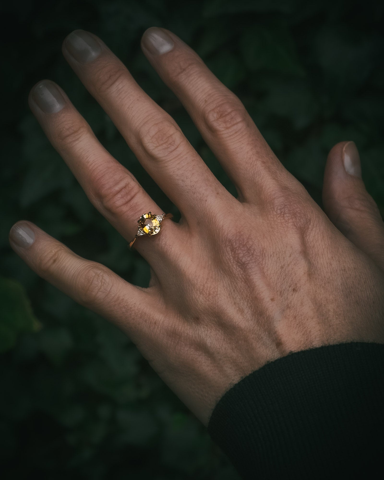 
Fidra bi-colour yellow and orange sapphire ring on hand; oval mixed-cut centre stone