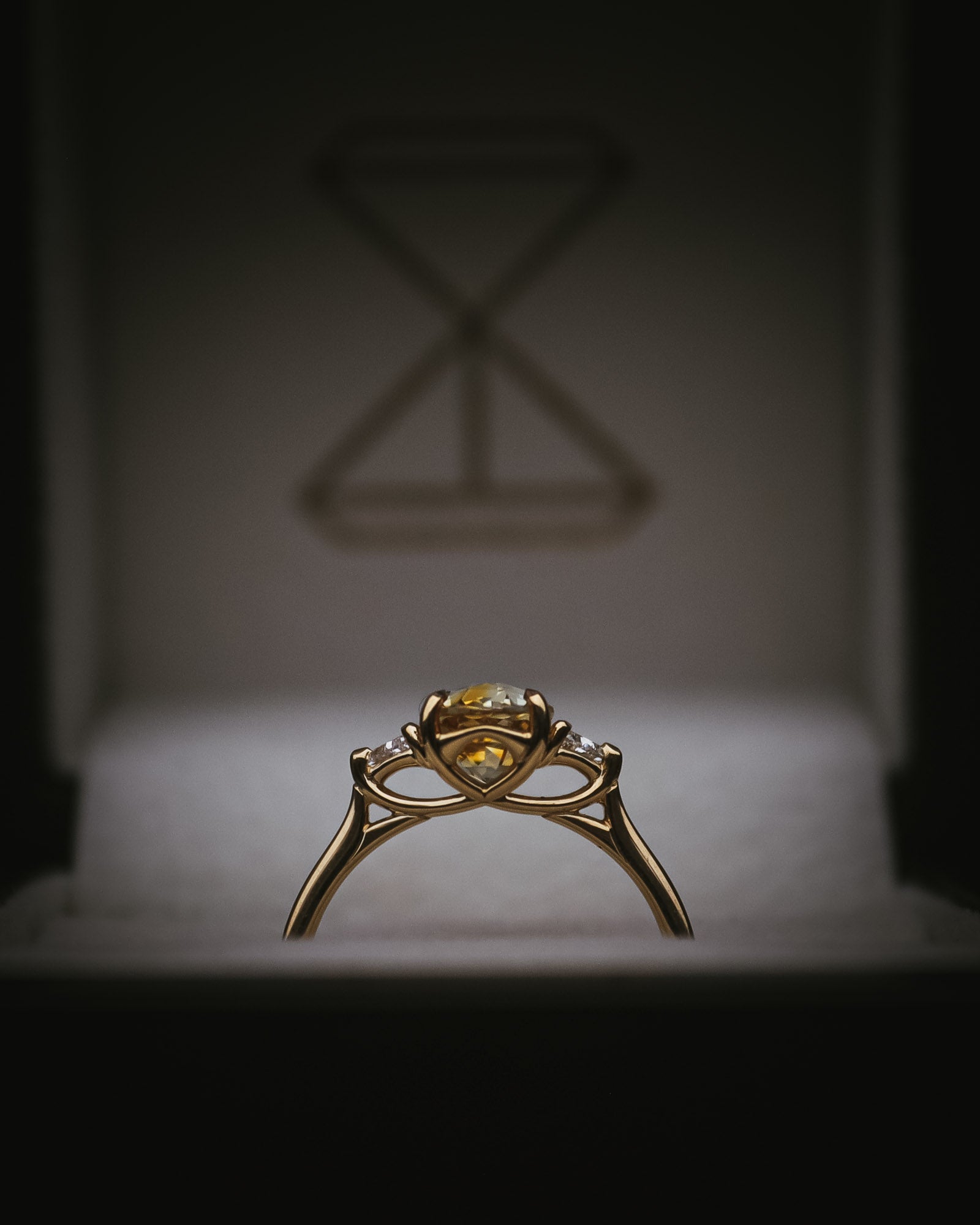 Fidra oval bi-colour sapphire ring; side profile showing Arc setting and trillion diamonds in box